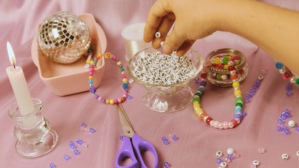 A hand is holding a pair of scissors while making a beaded bracelet