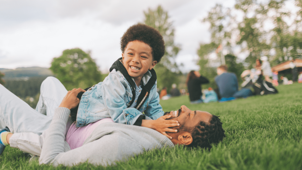 A father and son sitting on the grass in a park