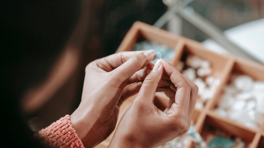 A hand is holding a pair of scissors while making a beaded bracelet