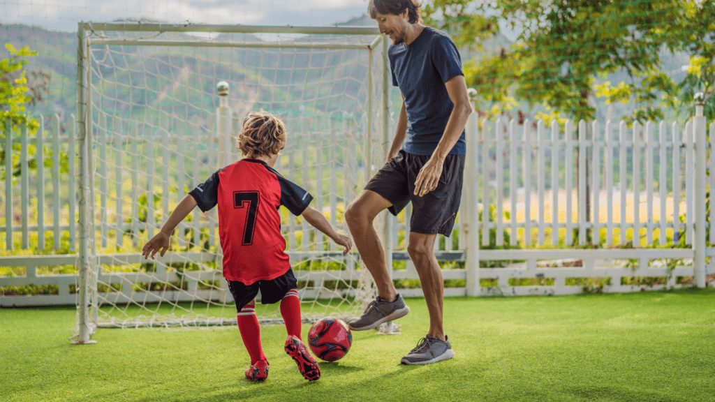 A parent and child playing soccer on artificial grass