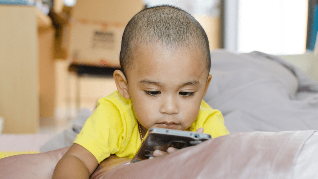 A person sitting on a bed playing with a cell phone