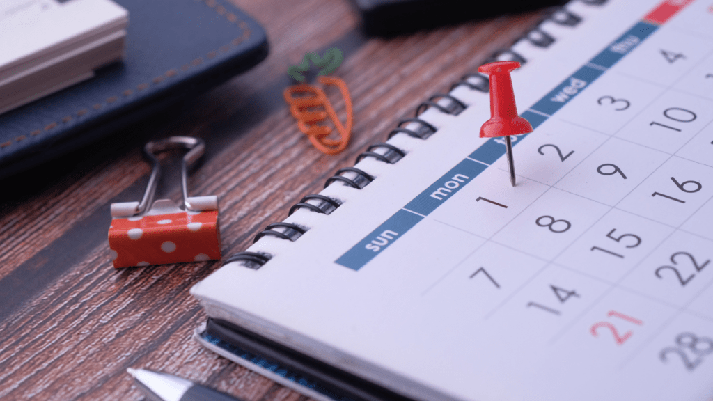 a calendar with a red pin on top of it on a desk