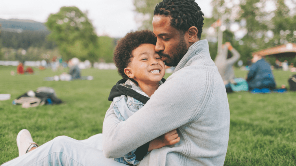 A father and son sitting on the grass in a park