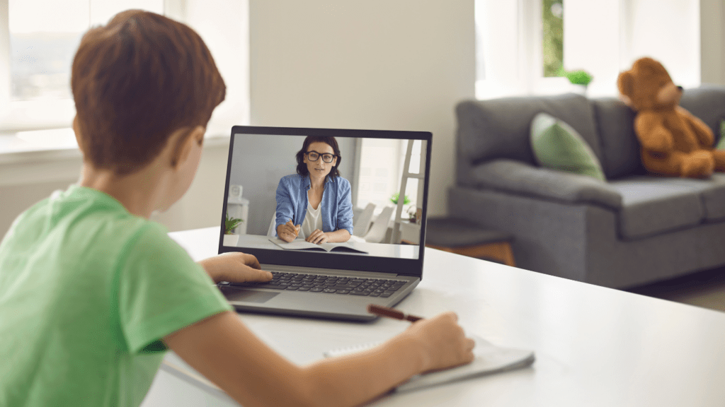 a child sitting at the table using a laptop