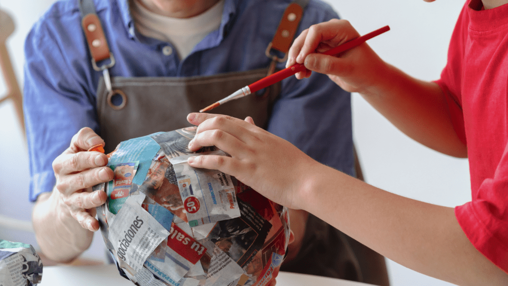 Two individuals are working on a paper ball.