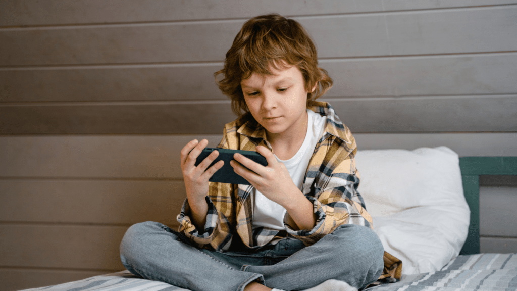 A person sitting on a bed playing with a cell phone