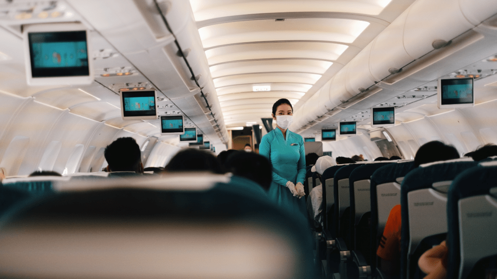 a person wearing a face mask stands in the aisle of an airplane