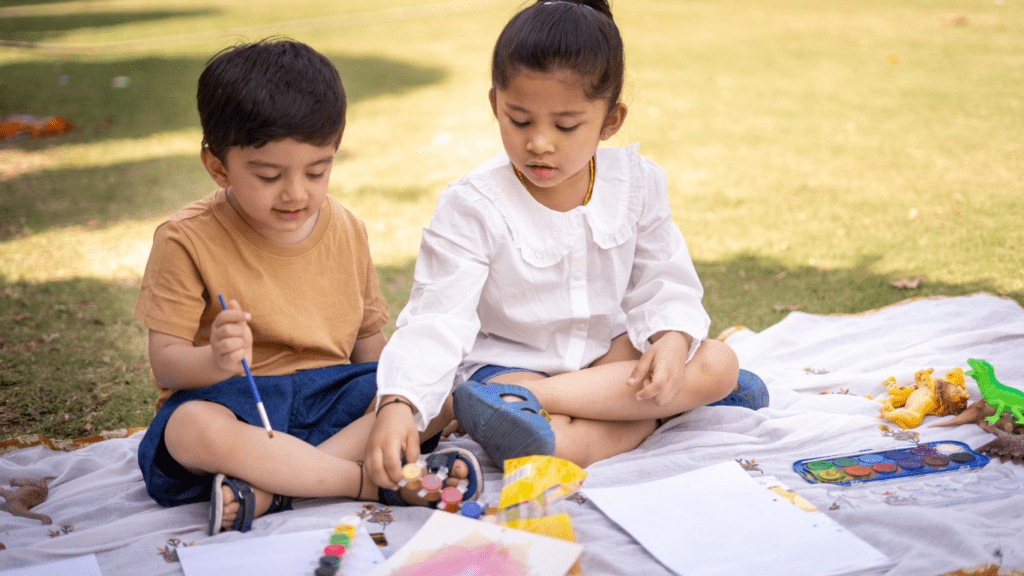 two children sitting on a blanket in the grass