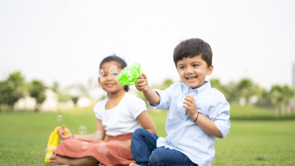 two children playing with bubbles in the grass