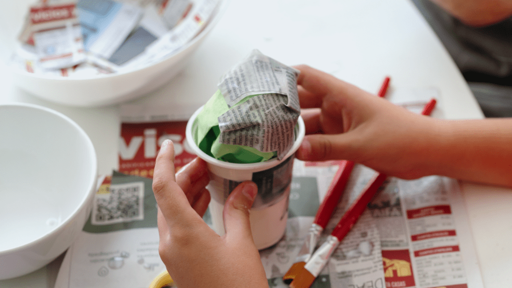 Two individuals are working on a paper ball.