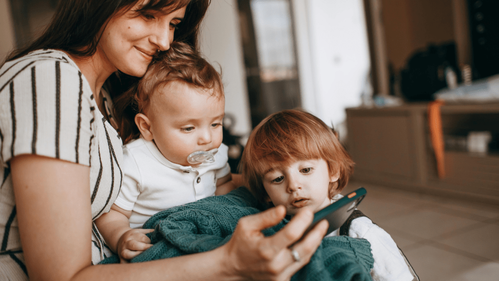 Two individuals holding a baby while looking at a tablet