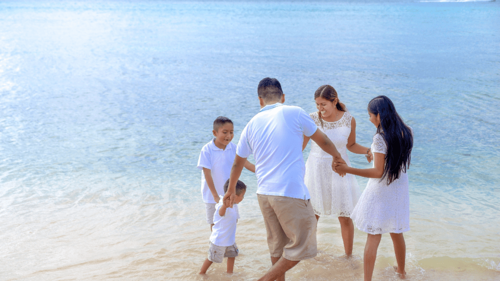 a family standing in shallow water on the beach