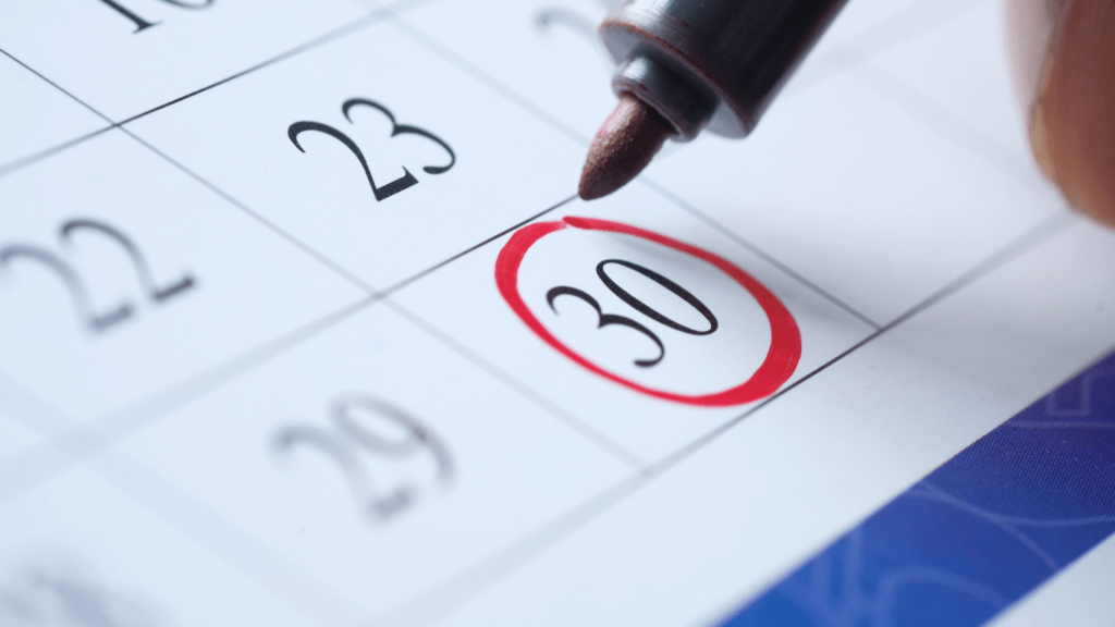 a calendar with a red pin on top of it on a desk