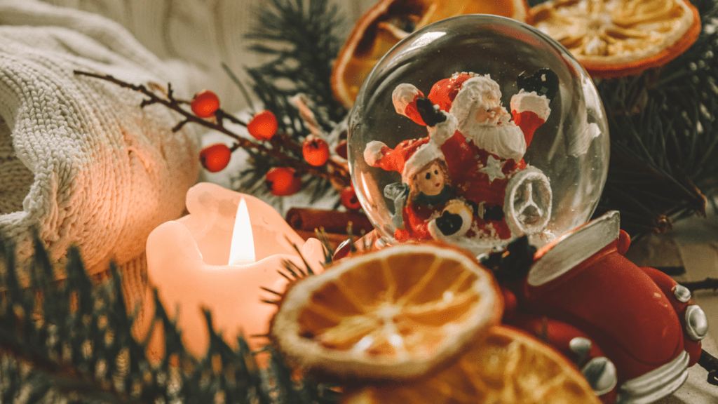 a christmas decoration with oranges, candles and a santa claus figurine