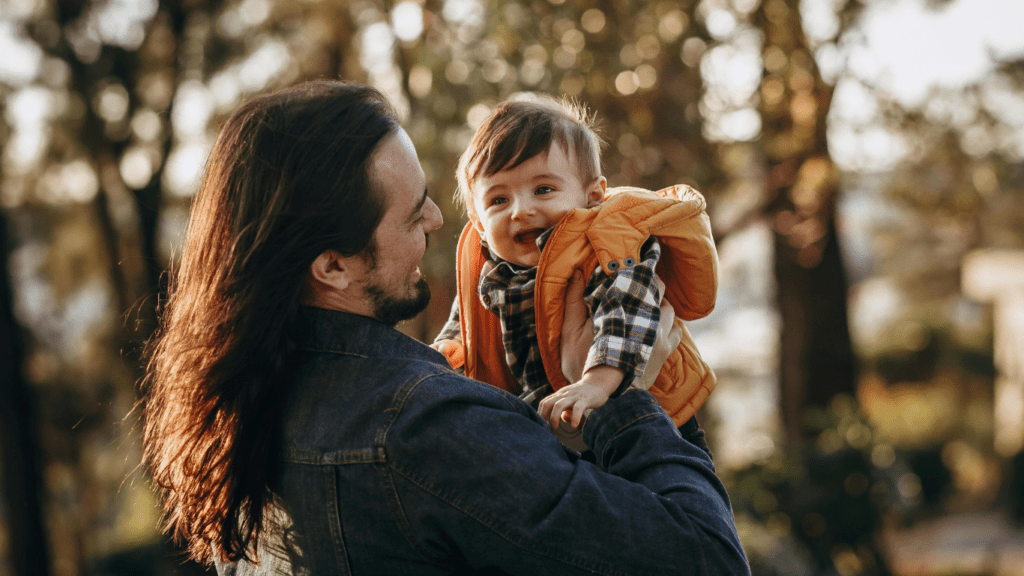 a person holding a baby in their arms while walking down the street