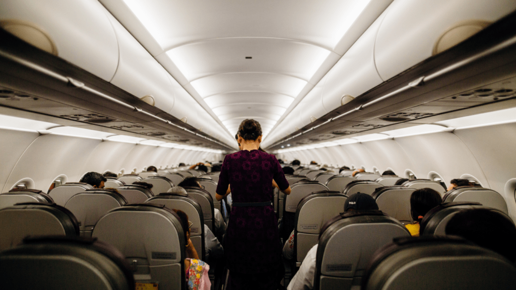 a person wearing a face mask stands in the aisle of an airplane