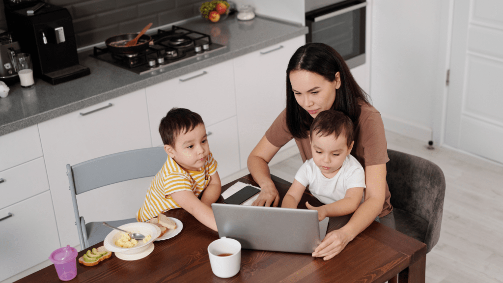 children and a person sitting at a table with a laptop