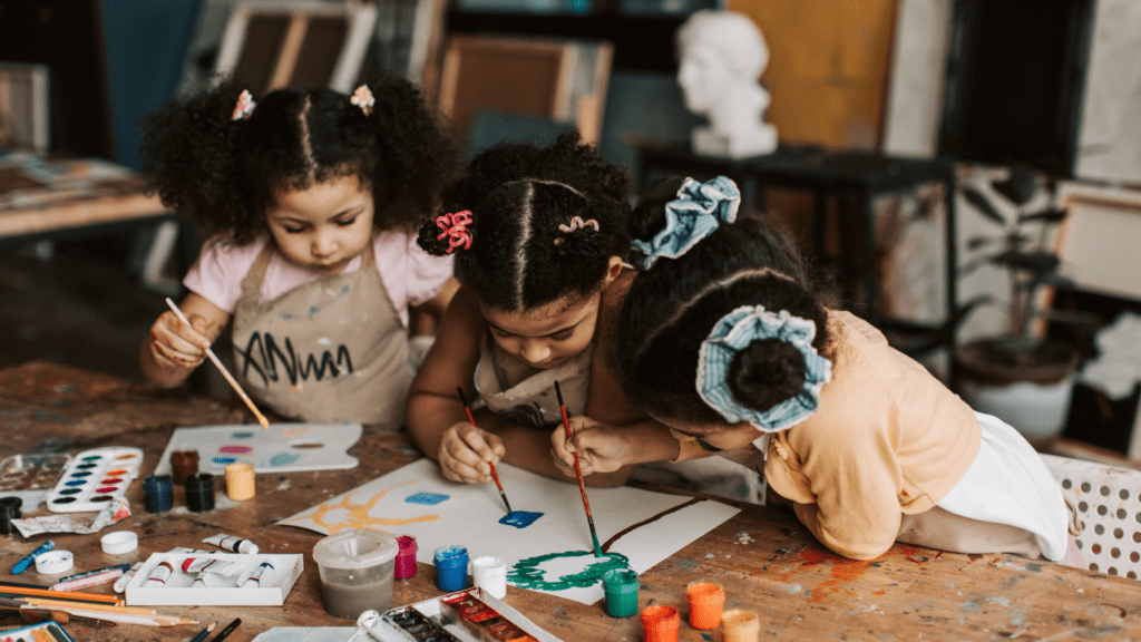 children are painting at a table in an art studio