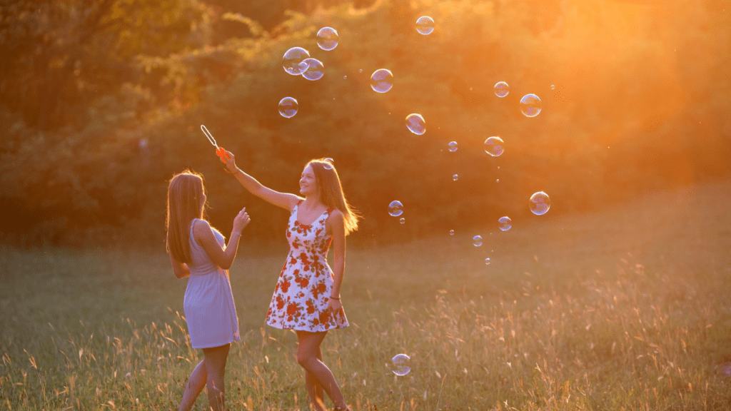 two children playing with bubbles in the grass