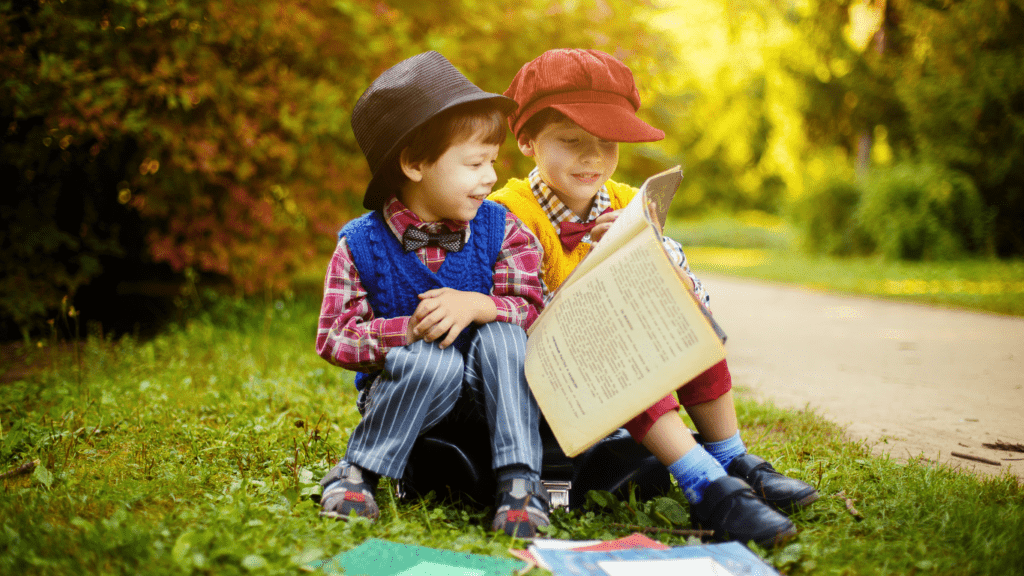 two children sitting on a blanket in the grass